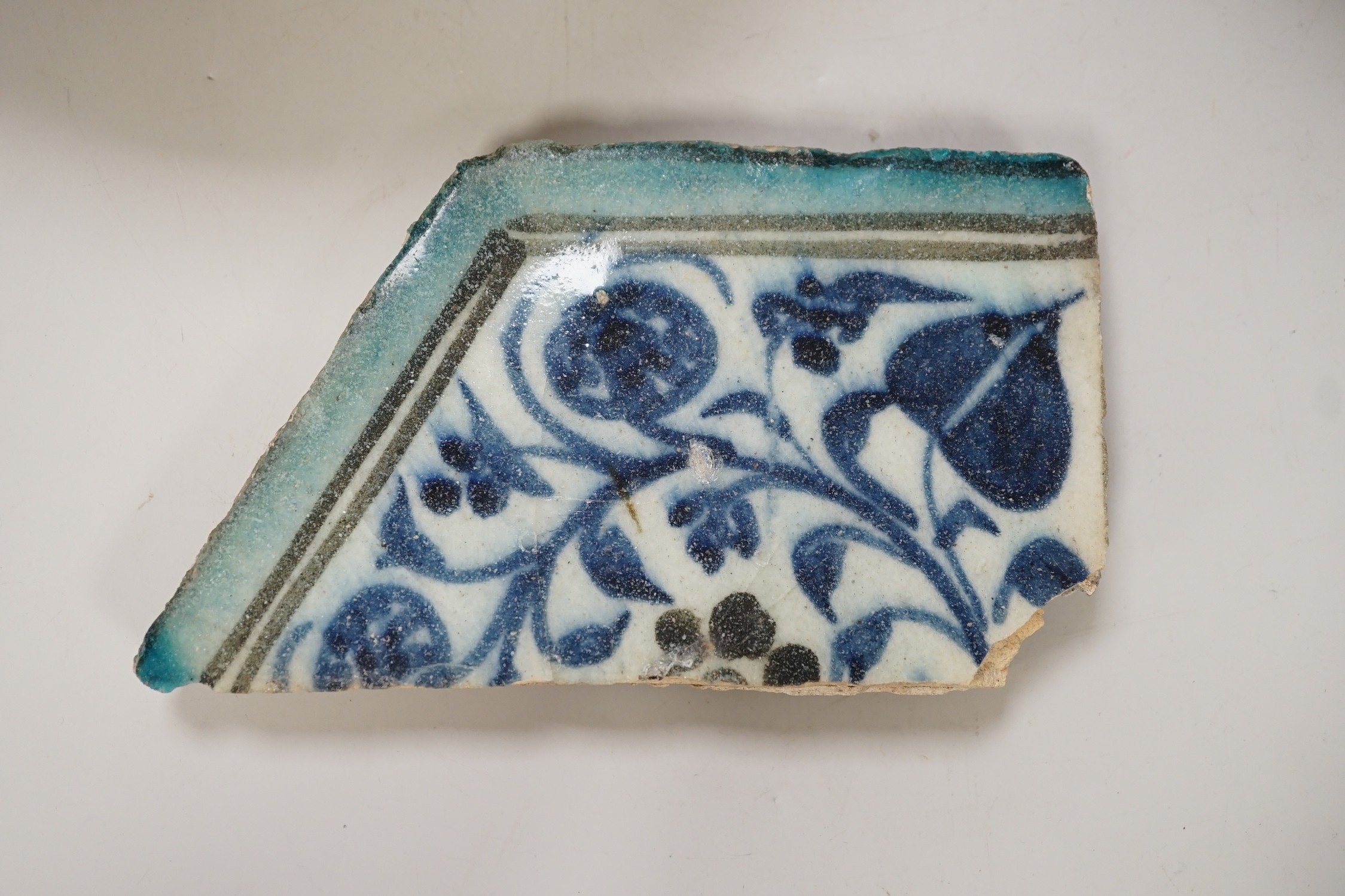 An Islamic Persian bowl with turquoise blue leaf design, 15cm diameter, together with a section of an Islamic tile, and another Islamic bowl, possibly Kashan. Tallest 11cm